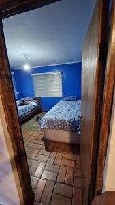 a bedroom with two beds and a blue wall at Casa Equipada Piscina Quincho Refugio Los Cerezos in Estación Cuñibal