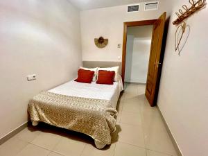 a bedroom with a bed with two red pillows on it at Apartamento céntrico junto paseo, playas y zonas de interés!! in Águilas