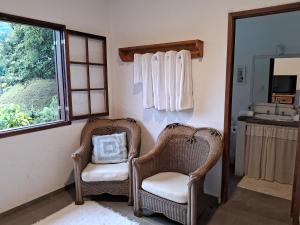 two wicker chairs sitting in a bathroom with a sink at Suites Caipira Vale das Videiras in Araras Petropolis