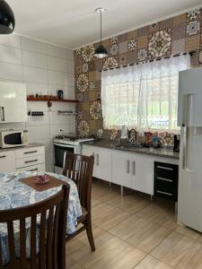 cocina con armarios blancos, mesa, mesa y sillas en Casa com vista para as montanhas, en Sapucaí-Mirim 30 fotos más