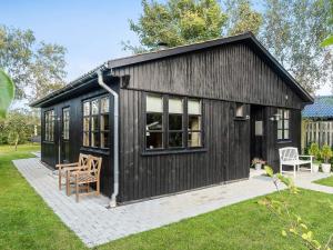 a black shed with a table and chairs in a yard at Cozy Summer House Near Ore Strand in Vordingborg