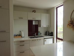 a kitchen with white cabinets and a sink at The Lookout- Clevedon in Clevedon +30 photos