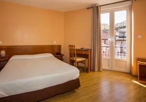 a bedroom with a bed and a desk and a window at Hotel le Dauphin in Ajaccio