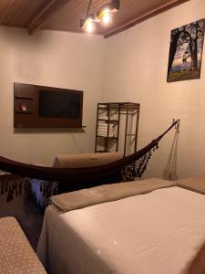 a living room with a hammock and a tv at Pousada Turmalina in Bueno Brandão