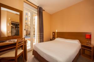 a bedroom with a bed and a desk and a window at Hotel le Dauphin in Ajaccio