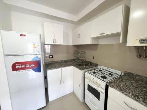 a kitchen with white cabinets and a white refrigerator at Apart San Jose in Villa Carlos Paz