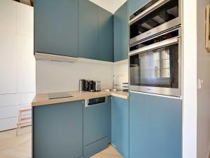 - une cuisine avec des armoires bleues et un réfrigérateur bleu dans l'établissement Modern getaway for two - Marais Place Vosges, à Paris 6 autres photos