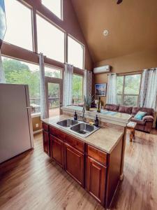 a kitchen with a sink and a living room with a couch at Treehouse 1 Mockingbird Lodge in New Braunfels