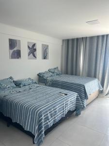 Dos camas una al lado de la otra en un dormitorio. en Flat makani carneiros tamandare, en Tamandaré