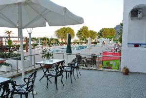 a patio with tables and chairs and a swimming pool at Kokalakis Hotel in Kefalos