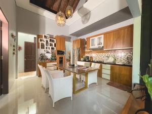 a kitchen with a dining table and white chairs at Villa Habibi in Uluwatu