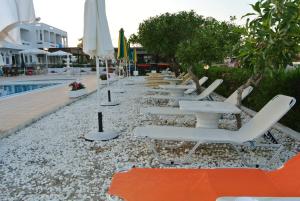 a row of lounge chairs and umbrellas next to a pool at Kokalakis Hotel in Kefalos