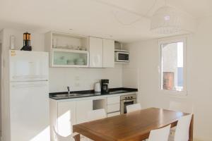 a kitchen with a wooden table and a white refrigerator at Complejo Espacio Marina in Villa Gesell