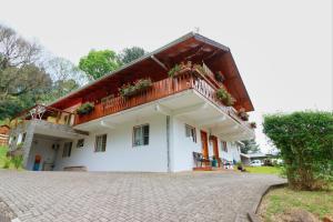 a white house with a balcony on top of it at Hospedaria Brigite - Apartamento de Férias in Treze Tílias