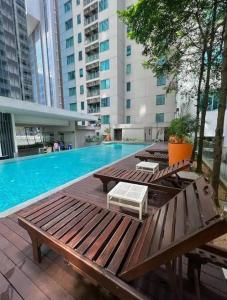 a swimming pool with wooden tables and benches in a building at SP Home At Mercu Summer Suites in Kuala Lumpur