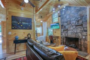 a living room with a stone fireplace and a leather couch at Firefly Haven - Summer Oasis with HOT TUB in Gatlinburg