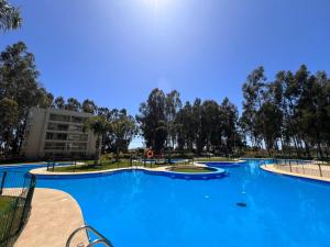 a large blue pool with trees in the background at Dpto Algarrobo in Algarrobo