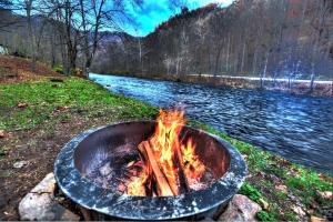 a fire pit in the grass next to a river at The Hala Lodge and Campground - Roadside Class II -1bed 1bath on Nantahala River in Bryson City