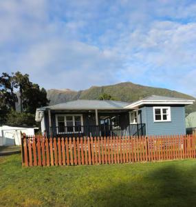 a house behind a fence with a mountain in the background at Glacier house in Fox Glacier