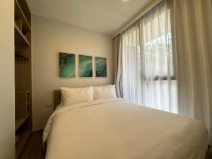 une chambre avec un grand lit blanc et une fenêtre dans l'établissement 2 BD Skypark Condo with Terrace, à Laguna Phuket