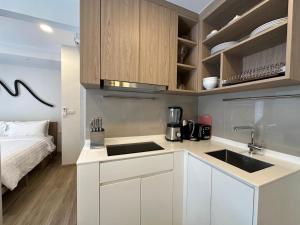 une cuisine avec des armoires blanches et un évier et un lit dans l'établissement 2 BD Skypark Condo with Terrace, à Laguna Phuket