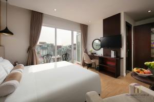 a hotel room with a large white bed and a balcony at Hanoian Central Hotel & Spa in Hanoi