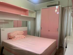 TanjungkarangZahran Guest House的一间小卧室,配有一张粉红色的床和一个衣柜