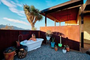 una donna in una vasca da bagno su un patio con piante di Sacred Sands - Lobo Luna a Joshua Tree