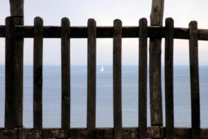 a fence with a sailboat in the ocean behind it at Elia Apartments Sithonia in Elia