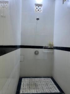a white shower with a black and white tile floor at Gladstudio in Kerobokan
