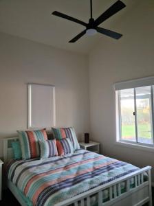 a bedroom with a bed with a ceiling fan at The Dairy FarmGate366 Blackhead Road in Hallidays Point