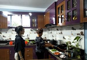 Due donne in piedi in una cucina a preparare il cibo di Peace Homestay a Kathmandu