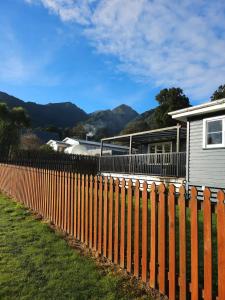 a fence in front of a house with mountains in the background at Glacier house in Fox Glacier
