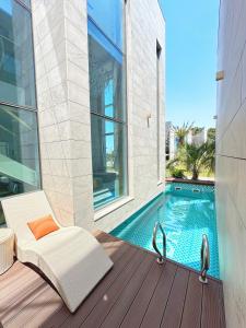a white chair sitting on a deck next to a swimming pool at Eudaimonia Poolvilla Jeju 에다모니아 함덕풀빌라 in Jeju