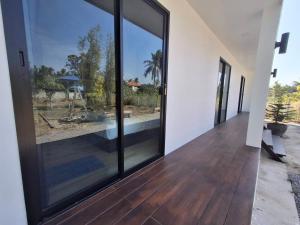 a large glass door with a view of a yard at Homlomchomsuan หอมลมชมสวน in Ban Mai +5 photos