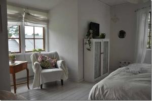 a bedroom with a bed and a chair and window at B&B Åvägen in Åhus