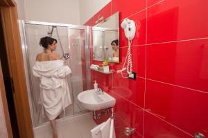 une femme debout dans une salle de bains avec lavabo dans l'établissement Hotel Accademia, à Bologne