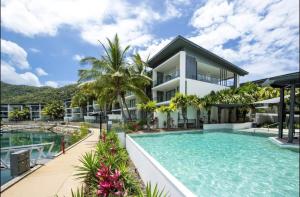a villa with a swimming pool and a house at Absolutely Lovely Waterfront Apartment 333 in Nelly Bay