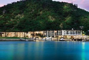 a building on the water with a mountain in the background at Absolutely Lovely Waterfront Apartment 333 in Nelly Bay