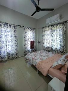 a bedroom with a bed and two windows with curtains at MiNi HoMeSTaY MuslIimOnly in Banting