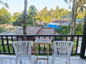 a balcony with two white chairs and a table at MookSkyDawBungalow in Trang
