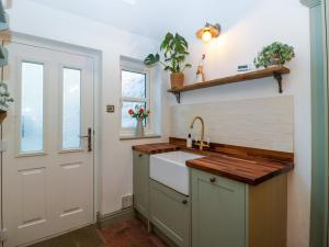 a kitchen with a sink and a door at Holly Cottage in Malvern Wells
