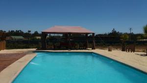 a blue swimming pool with a gazebo at Cabañas Boutique il Bosco in Algarrobo