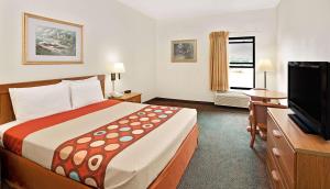 a hotel room with a bed and a flat screen tv at Super 8 by Wyndham Hampshire IL in Hampshire