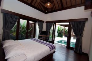 a bedroom with a bed and sliding glass doors at Villa Puspa in Tanah Lot