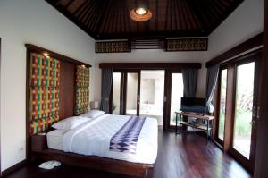 a bedroom with a bed and a television in it at Villa Puspa in Tanah Lot