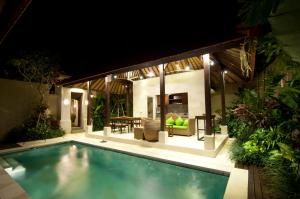 a swimming pool in front of a house at night at Villa Puspa in Tanah Lot