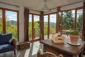 a living room with a wooden table and glass windows at Csillagfény Házikó in Nagymaros