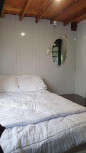 ein weißes Bett in einem Zimmer mit einem Spiegel in der Unterkunft Datu Villa Sembalun in Sembalun Lawang