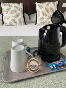 a tray with a coffee pot and cups on a bed at Cit'Hotel Les Atlantes Royan parking privé in Médis